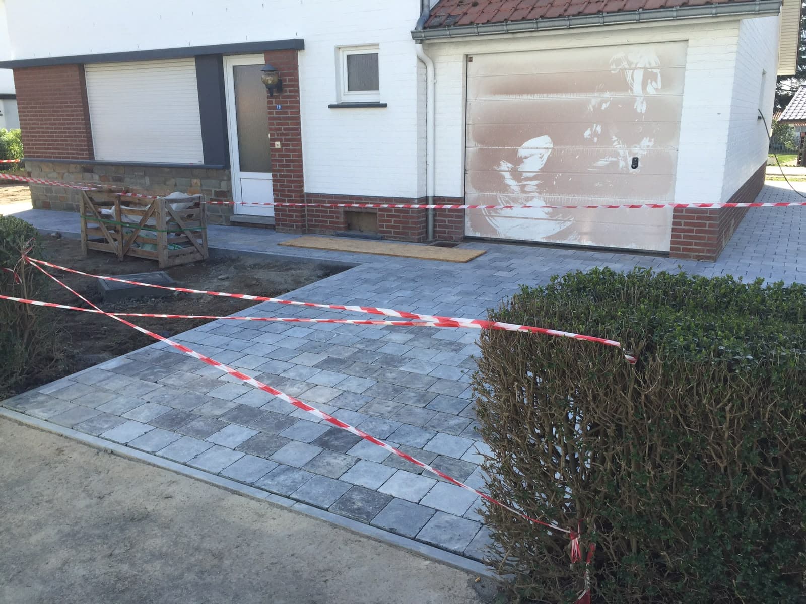 Allée pavée en cours de pose devant un garage