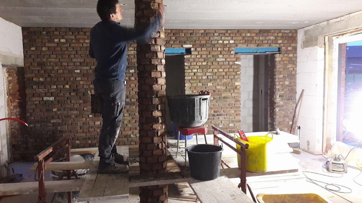 Artisan consolidant un pilier en briques dans une pièce en rénovation
