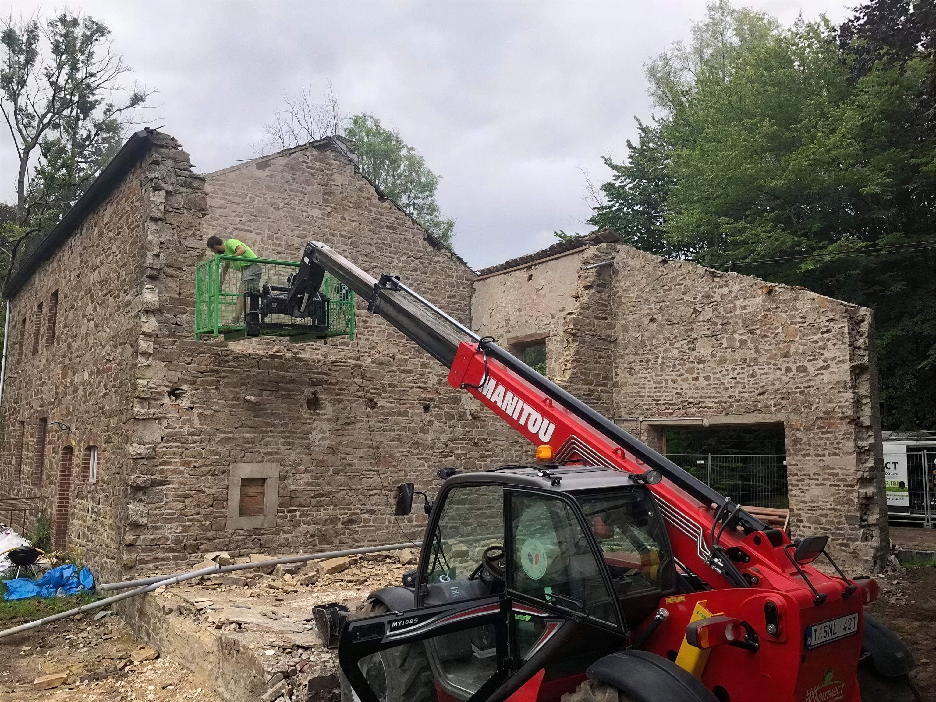 Chargeur télescopique levant des matériaux devant une maison en pierre en rénovation