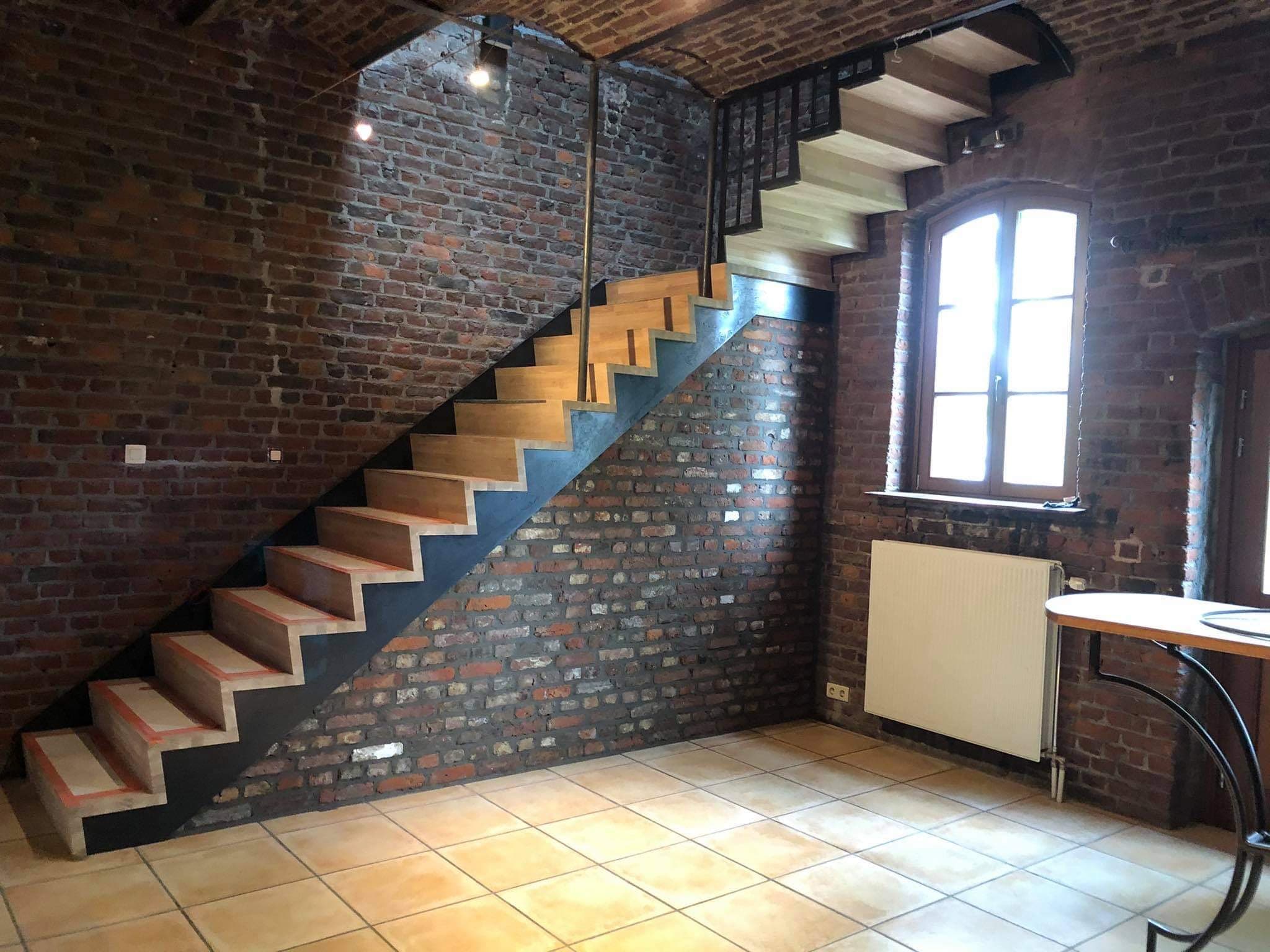 Escalier en bois le long d’un mur en briques anciennes