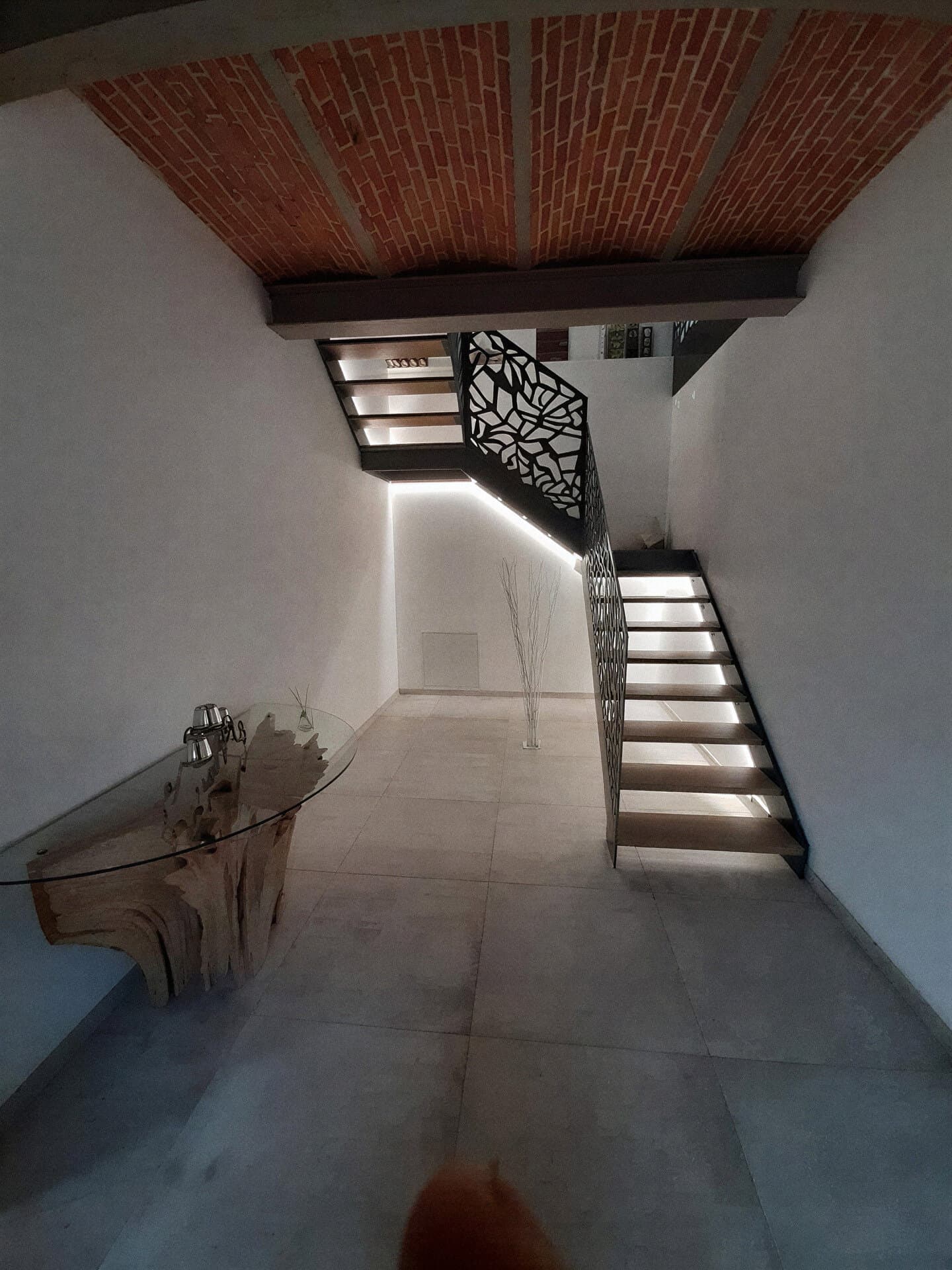 Escalier aux marches éclairées sous un plafond en voûtains de briques