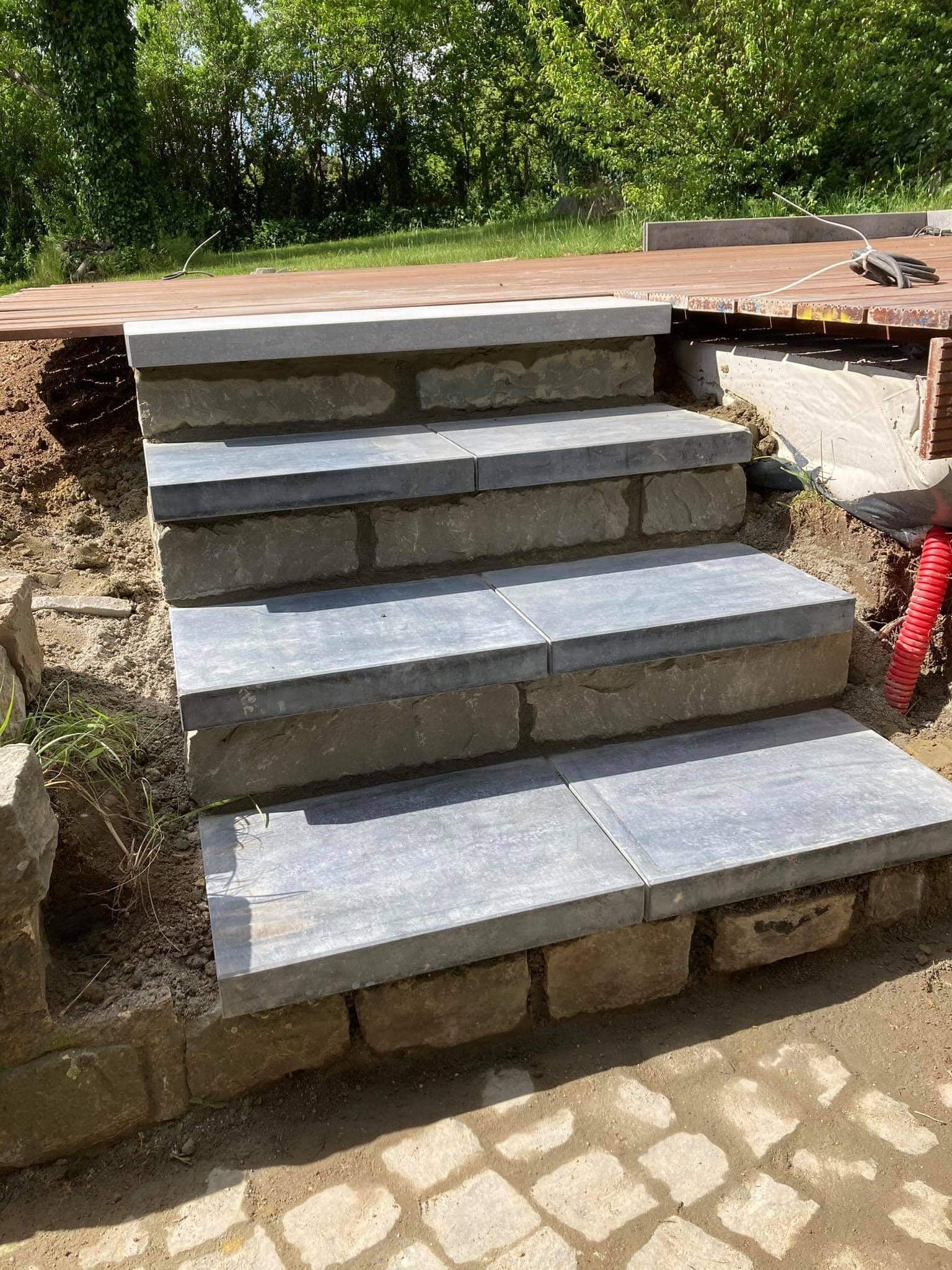 Marches d’escalier extérieur en pierre bleue posées sur un soubassement en pierre