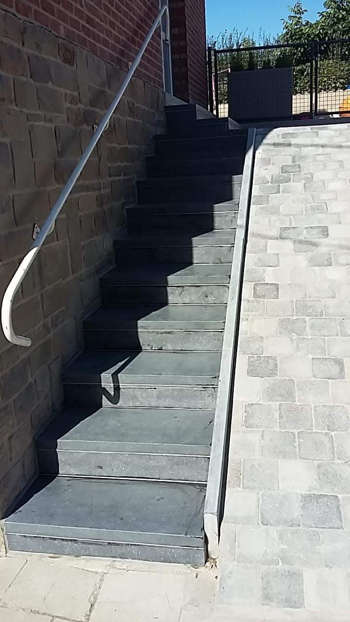 Escalier extérieur en pierre longeant un mur en briques