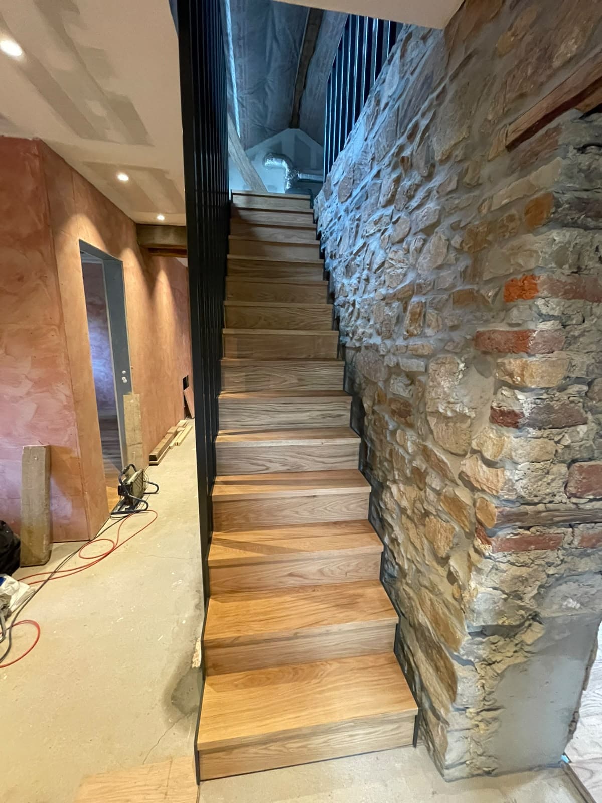 Escalier aux marches en bois le long d’un mur en pierre apparente