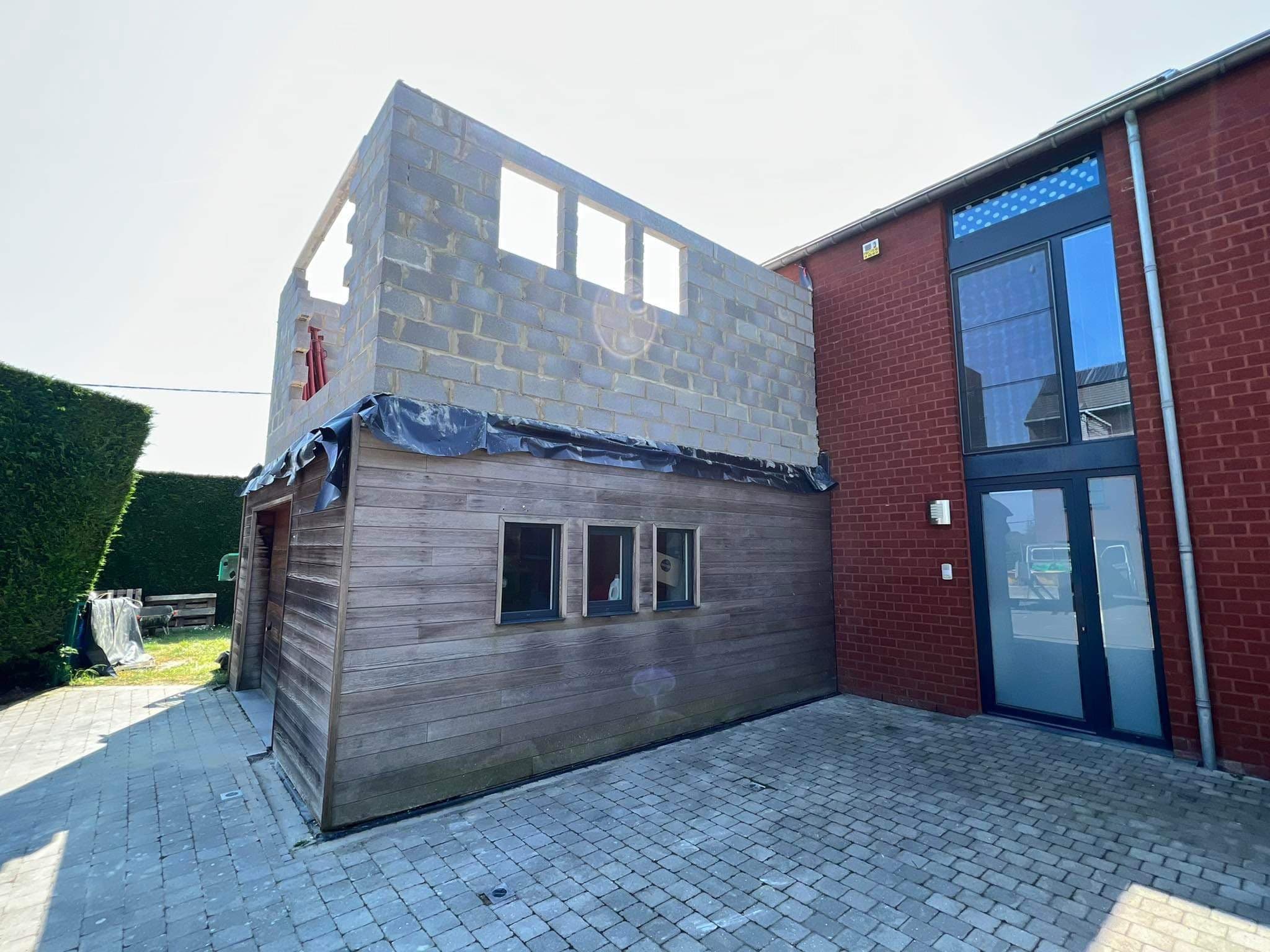 Extension en blocs en cours de construction contre une maison en brique