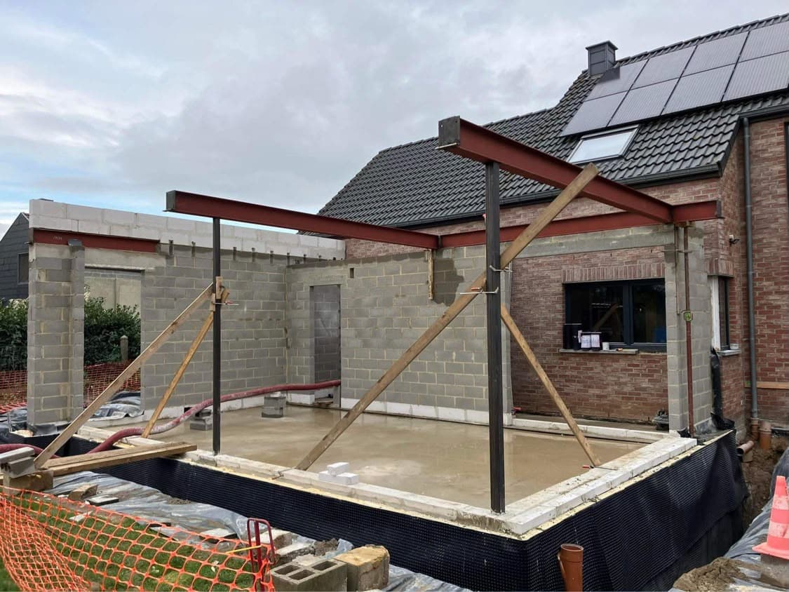 Extension en blocs avec poutres métalliques contre une maison existante