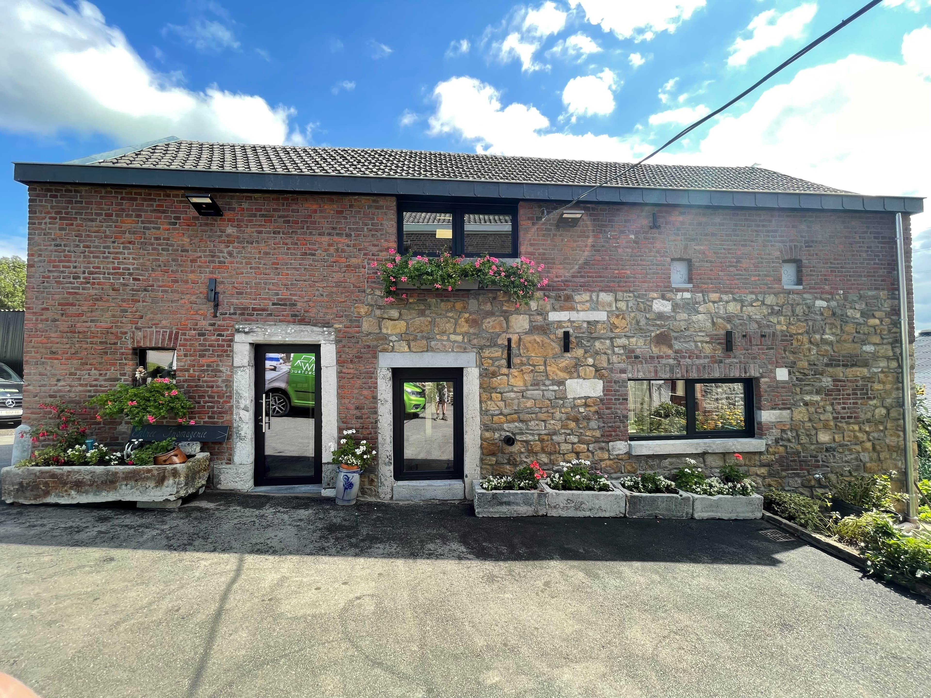 Façade en briques et moellons d’une maison de village restaurée, fenêtres fleuries