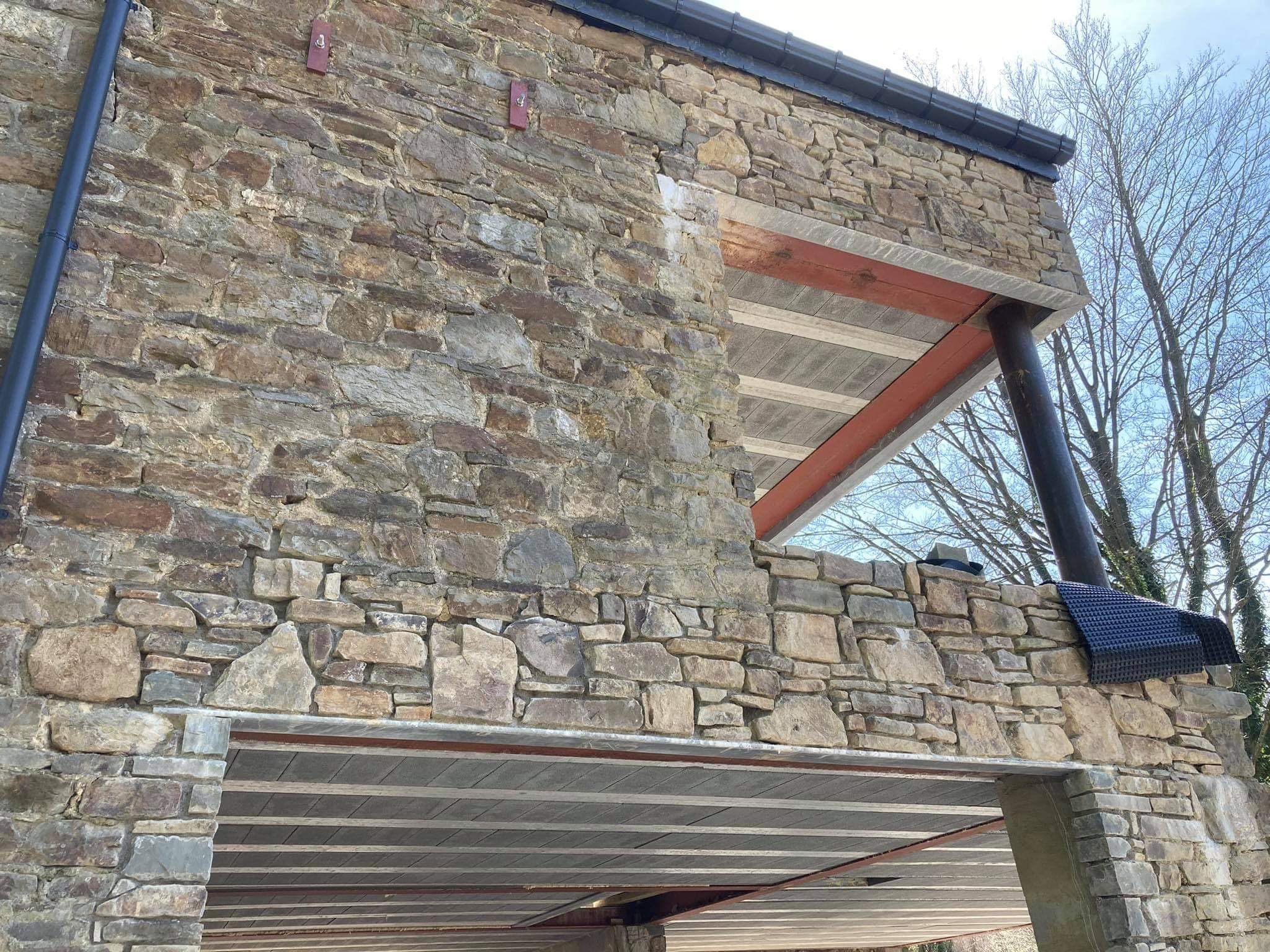 Façade en moellons restaurée sous un auvent