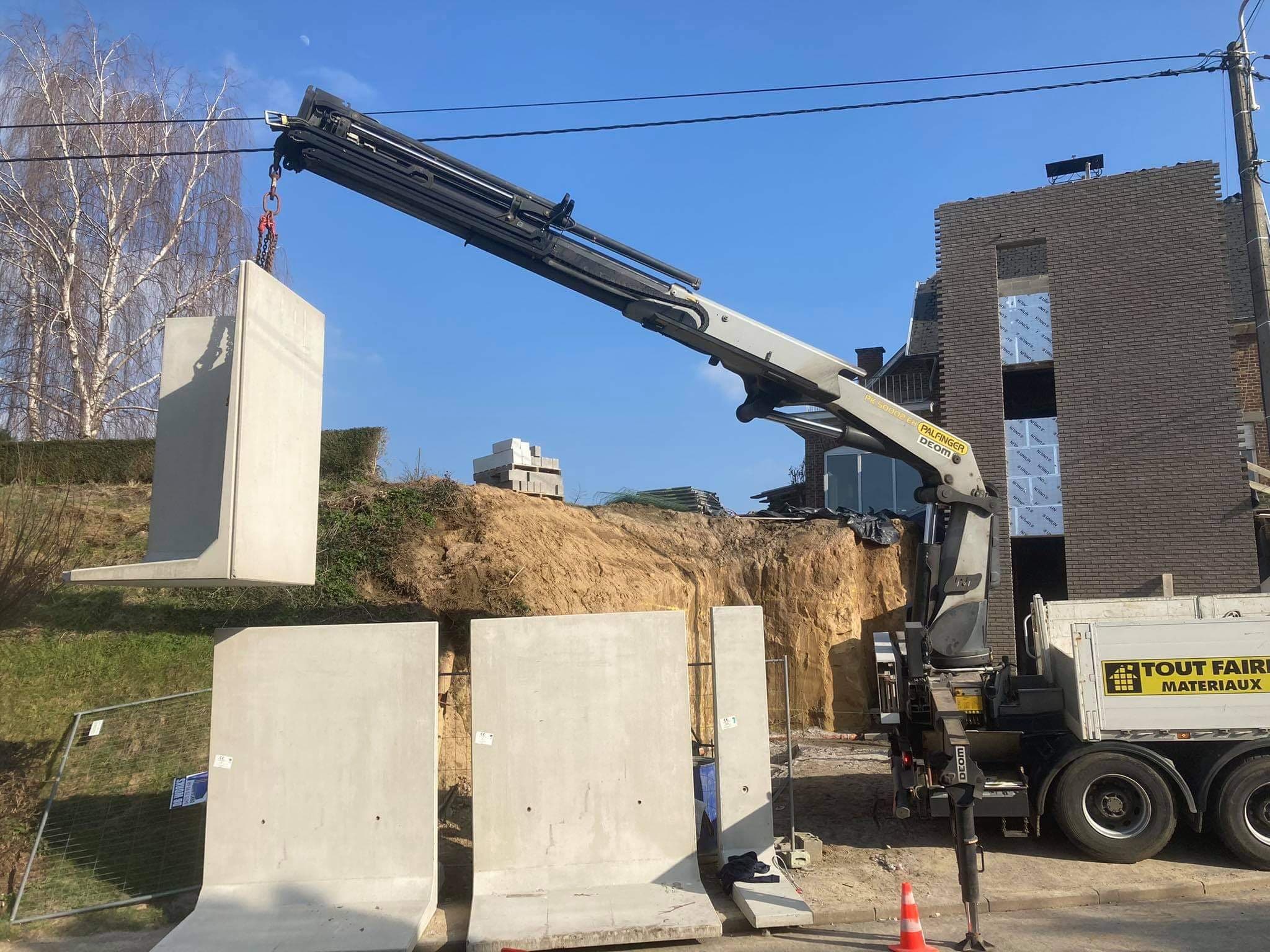Grue posant des éléments de mur en béton sur un chantier de construction