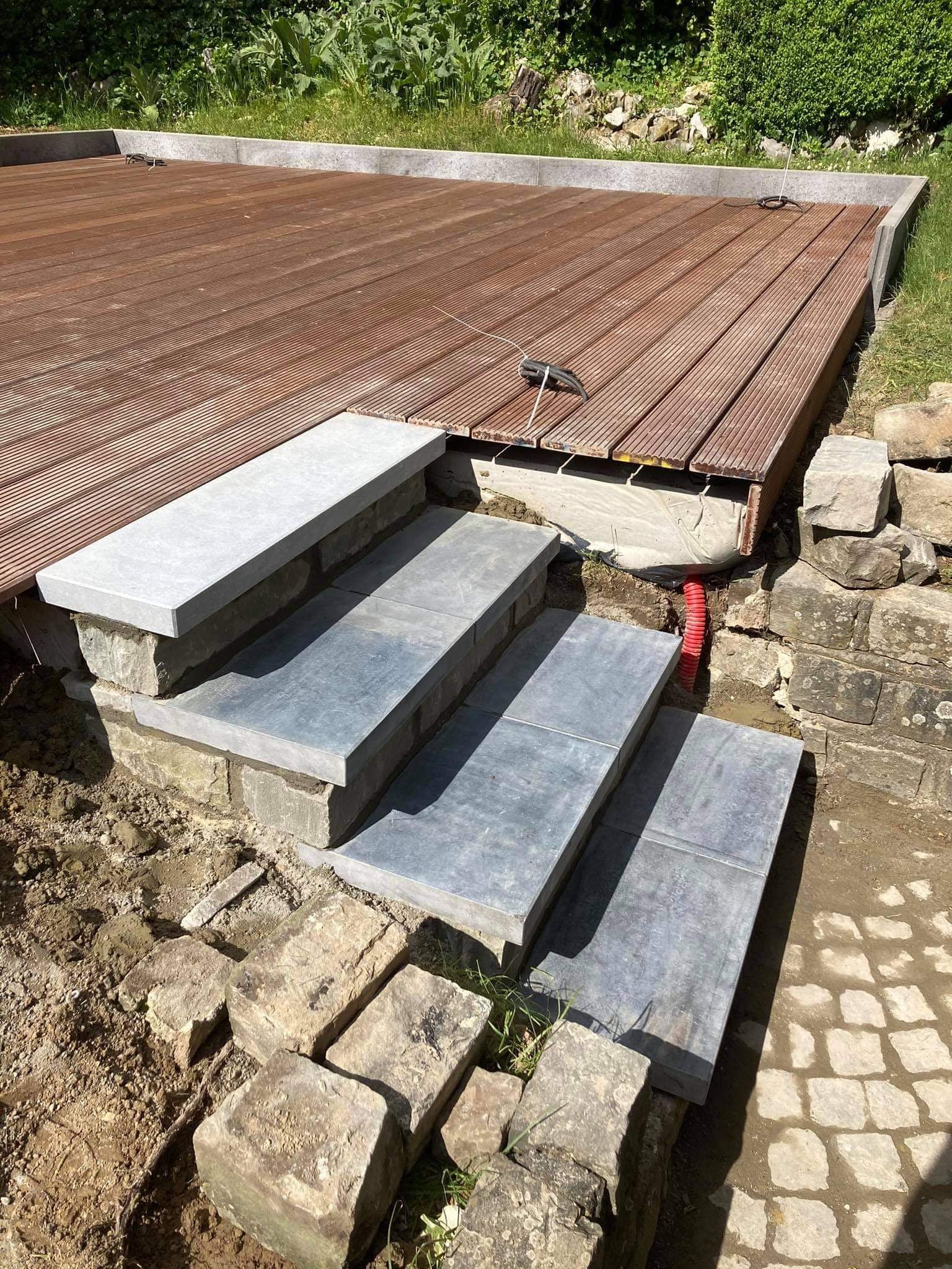 Marches en pierre bleue menant à une terrasse en bois en cours de pose