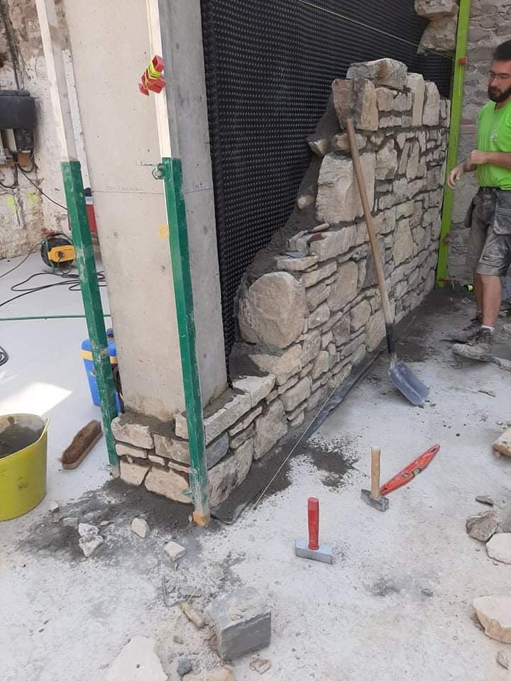 Mur en pierre en cours de remontage sur un chantier