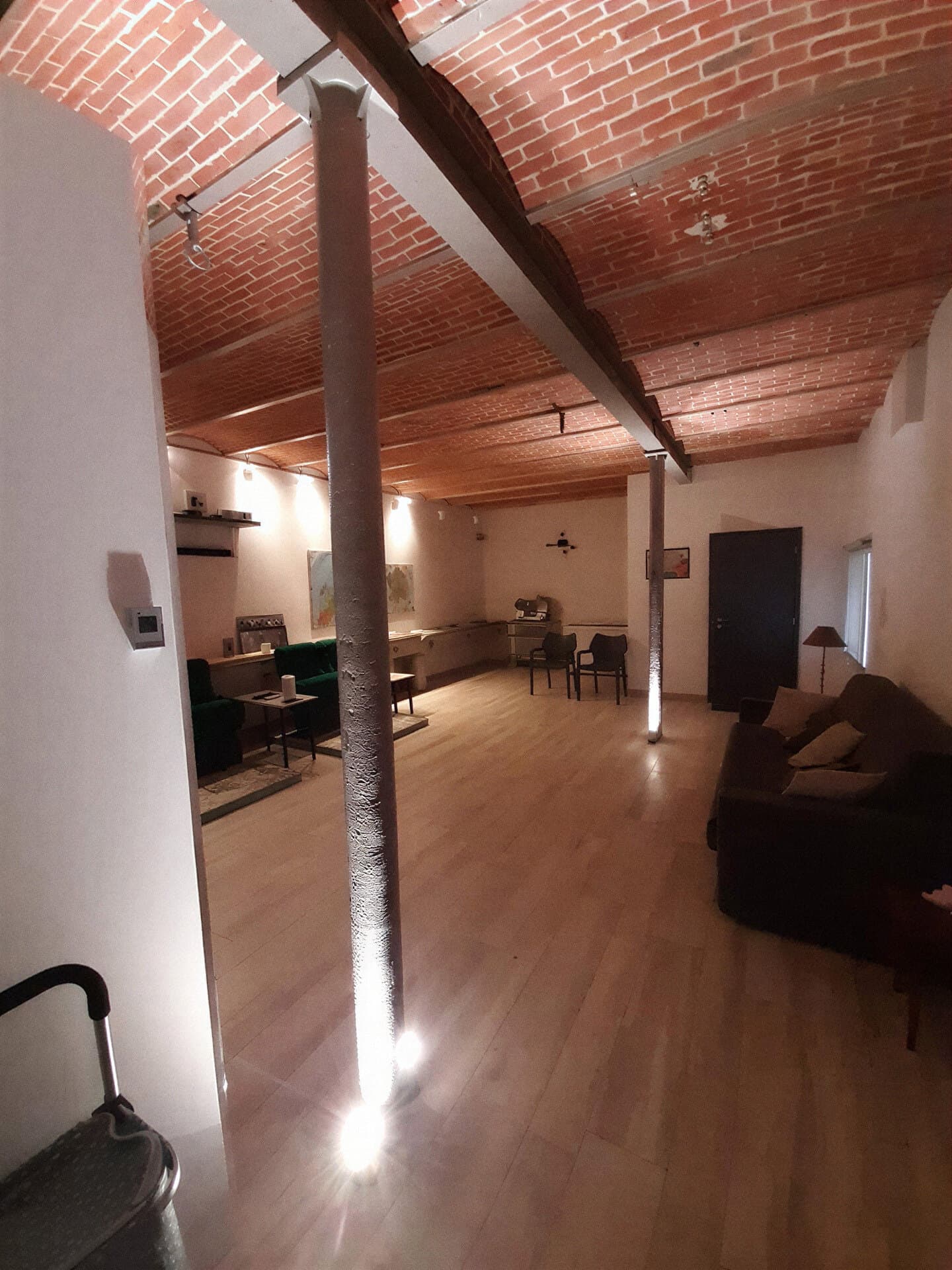Pièce de vie rénovée sous un plafond en voussettes de briques, colonne métallique au centre