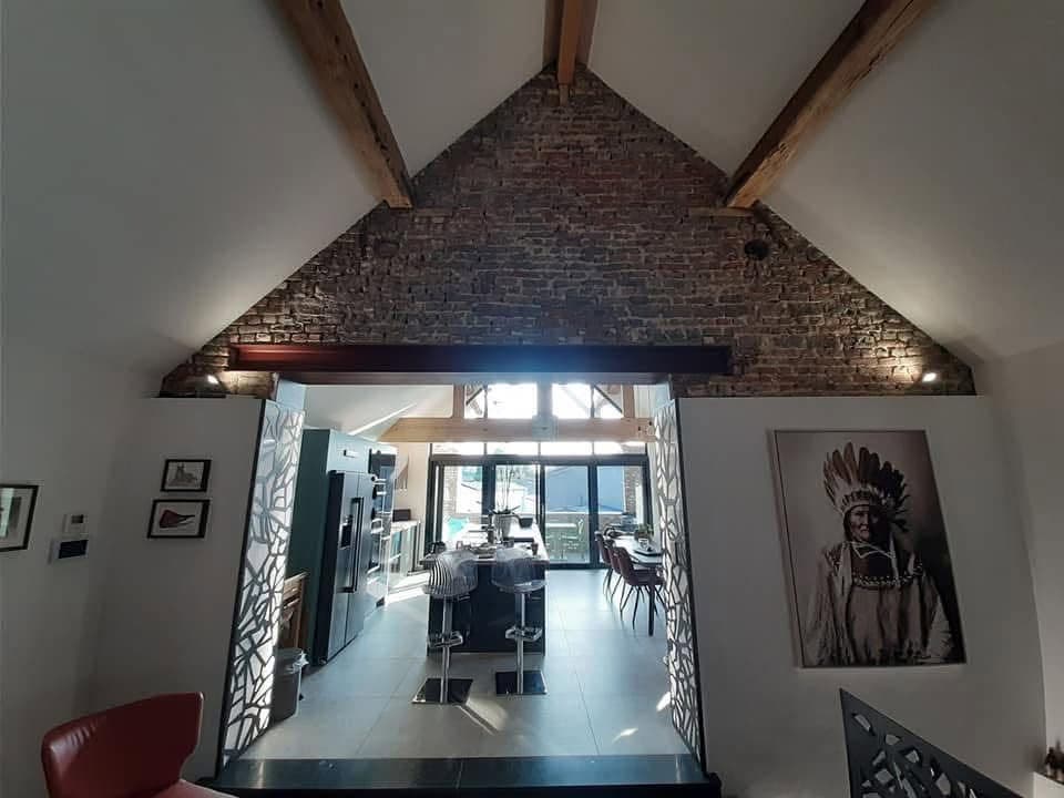 Pignon intérieur en briques apparentes sous une charpente, au-dessus d’une cuisine