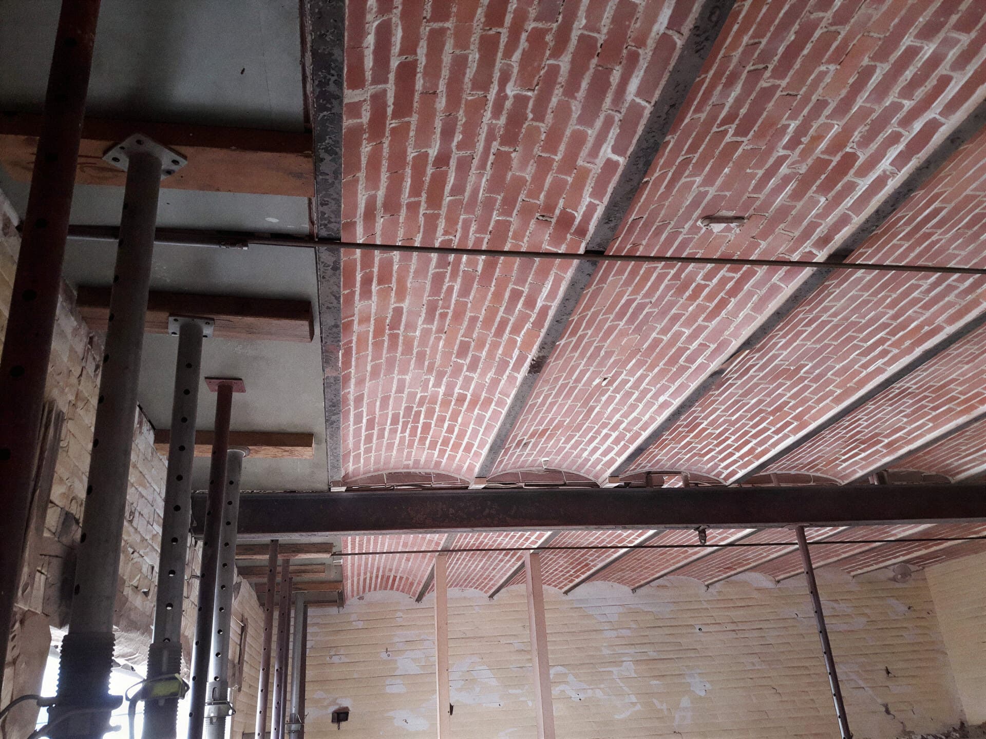 Plafond en voussettes de briques et poutrelles métalliques, soutenu par des étais pendant sa restauration