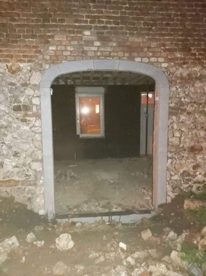 Porte cintrée avec encadrement en pierre dans un mur en briques