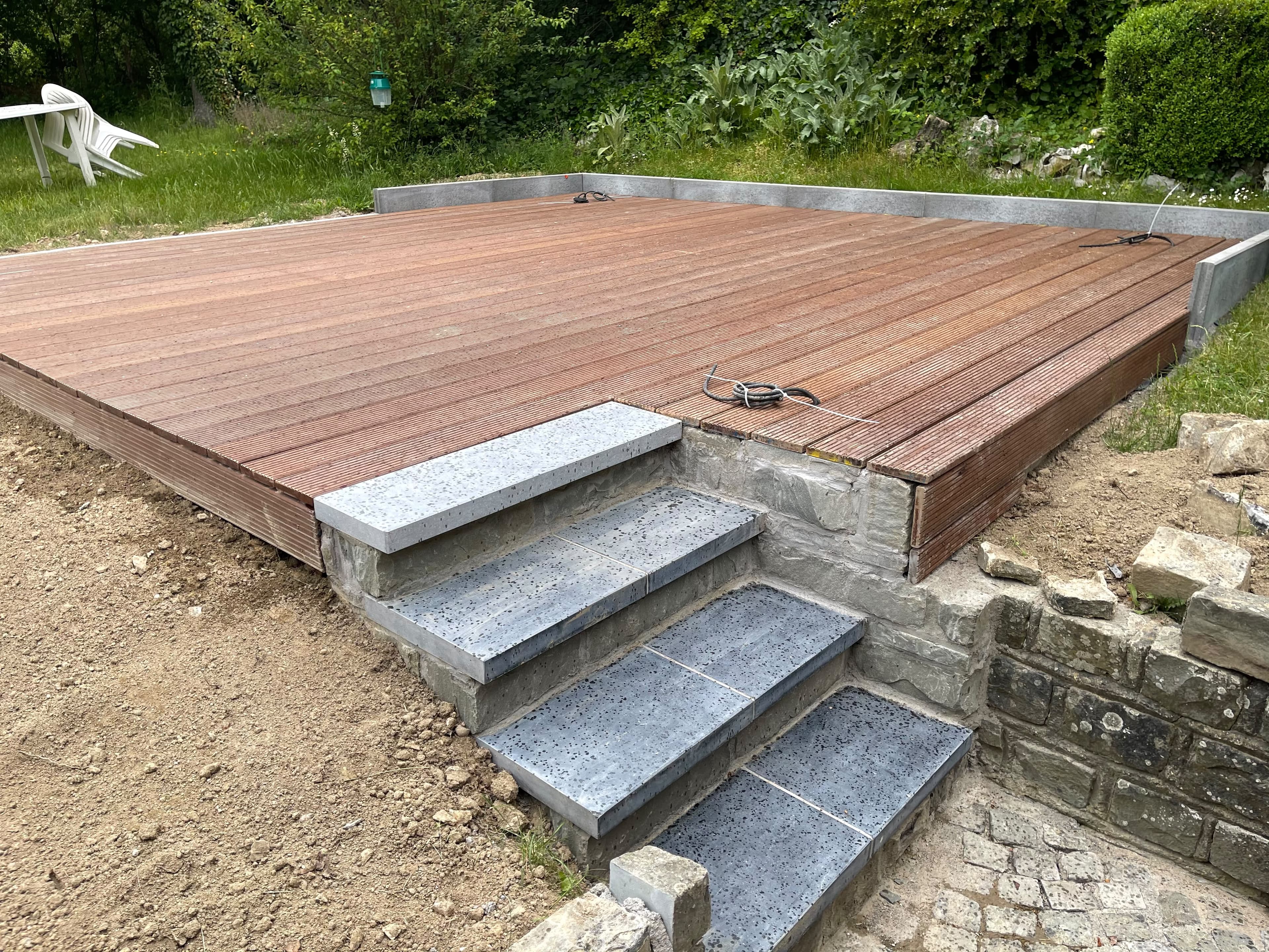 Terrasse en bois et marches en pierre bleue sur un muret en pierre